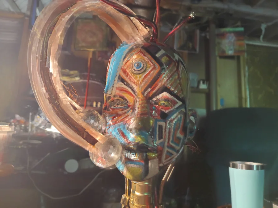 Mofasis in Flux — a masked head assemblage in gold, copper, and turquoise